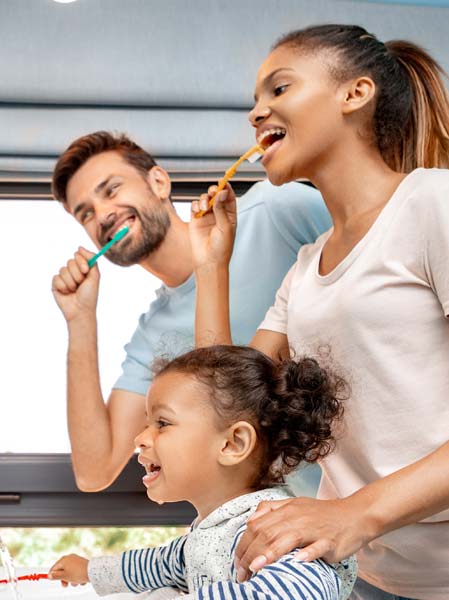 young family brushing teeth in front of mirror